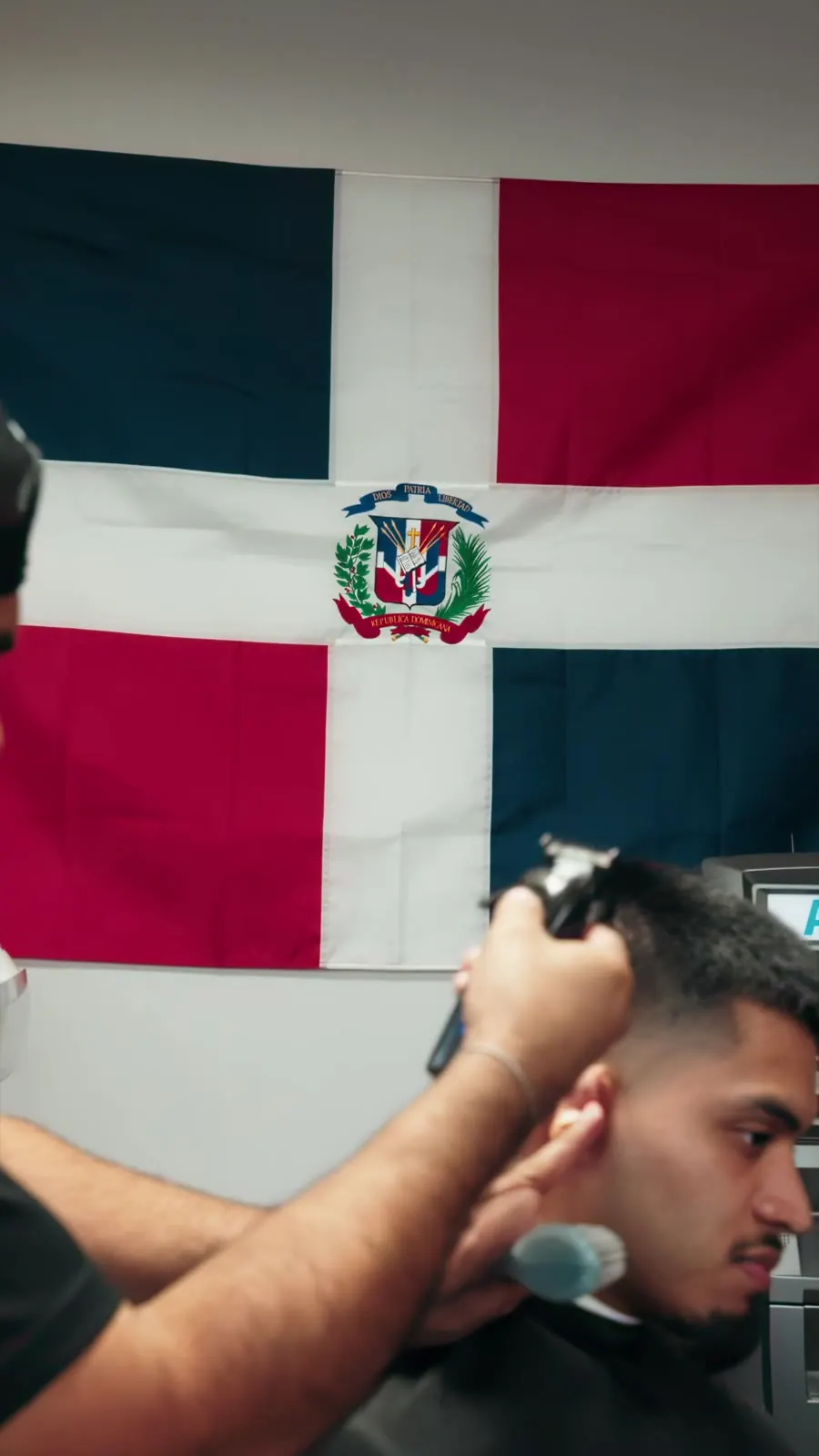 Barber cutting hair under the Dominican flag